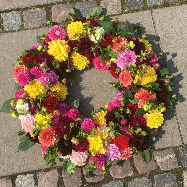Smuk kulørt rundtpyntet blomsterkrans til begravelse – vi leverer i Odder og opland
